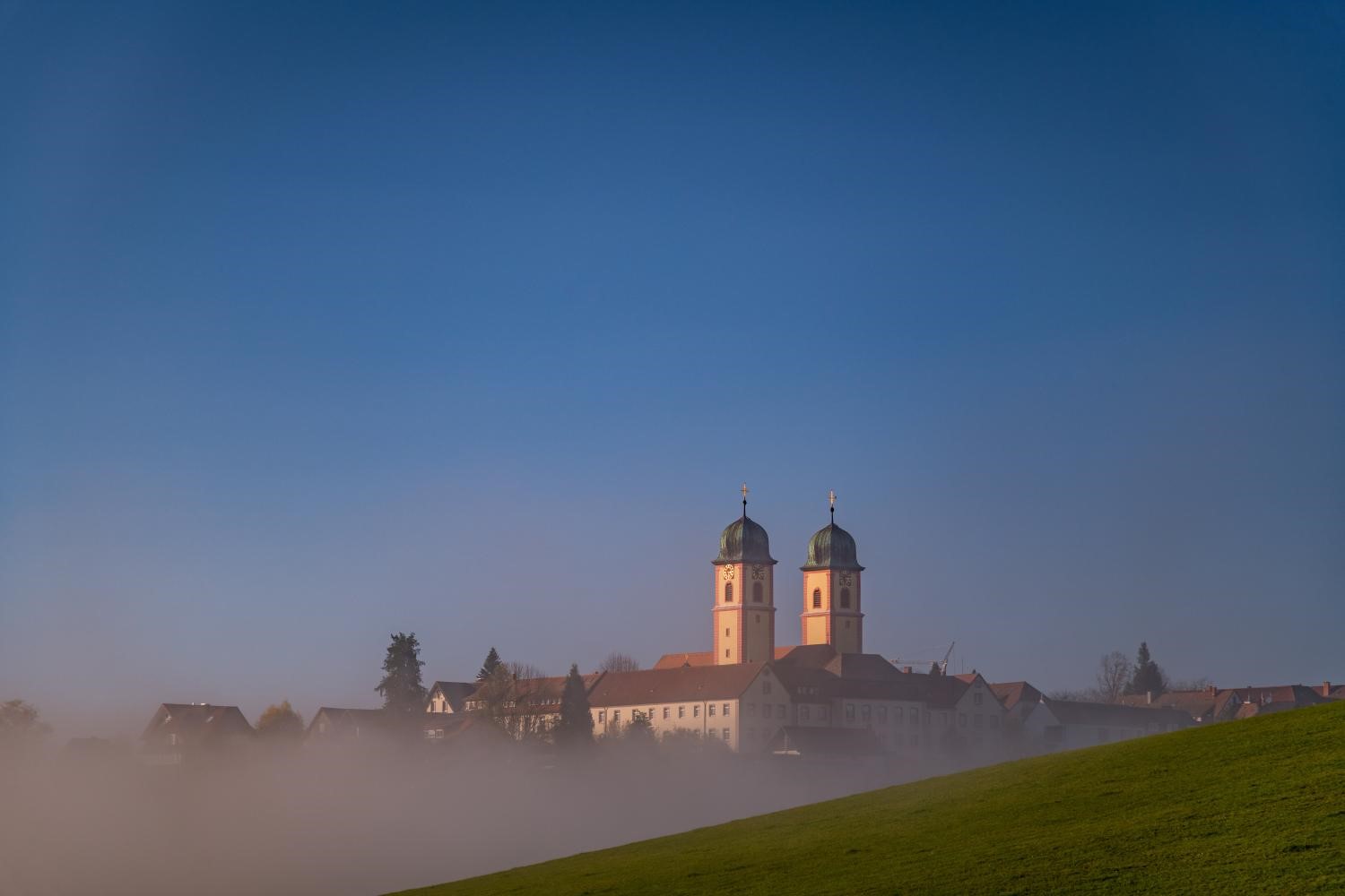 Klosterkirche mit zwei Türmen im Morgennebel