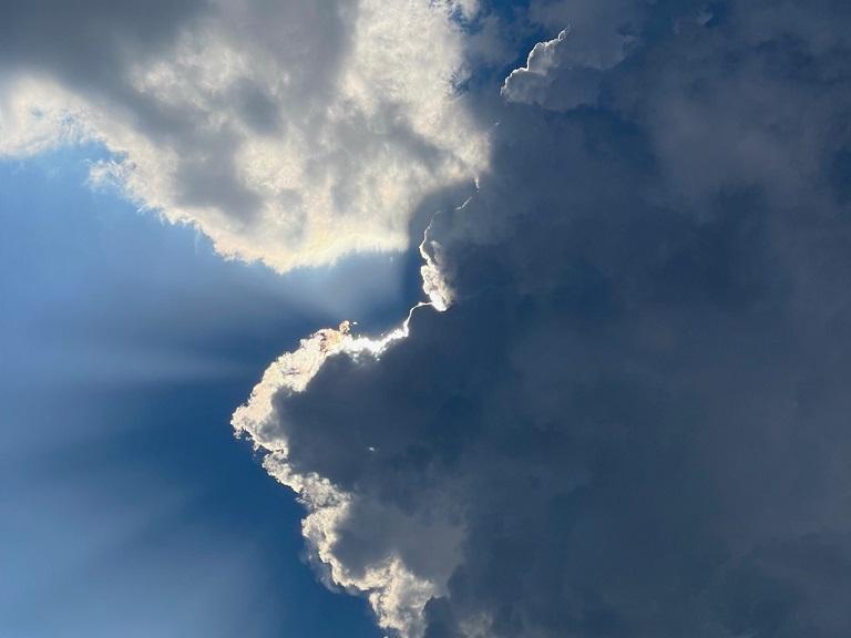 Sonnenlicht scheint hinter einer dunklen Wolke hervor.