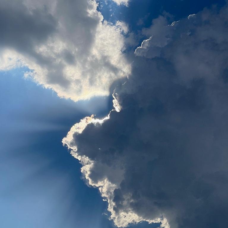 Sonnenlicht scheint hinter einer dunklen Wolke hervor.