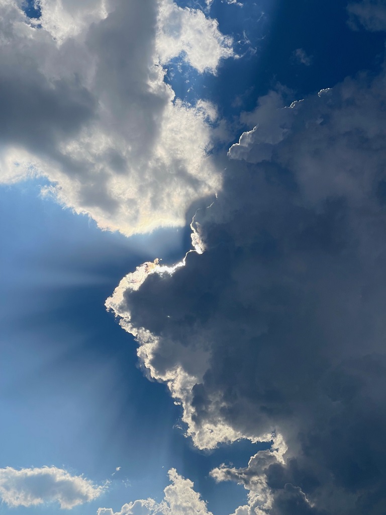 Sonnenlicht scheint hinter einer dunklen Wolke hervor.