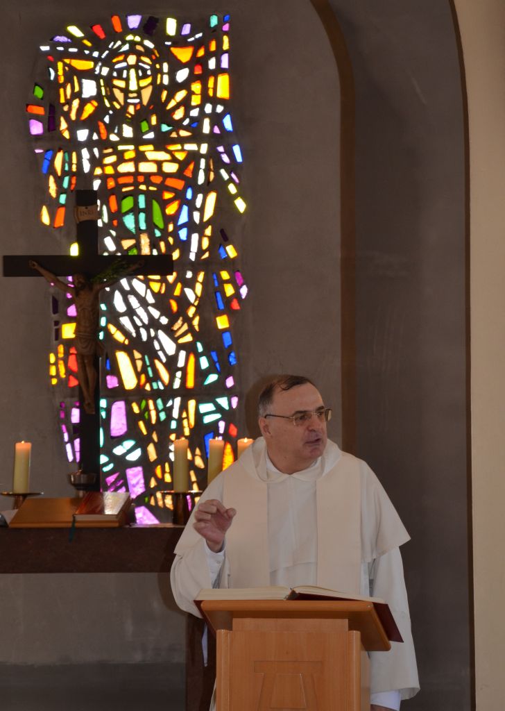 Ein Priester steht an einem Ambo und predigt.