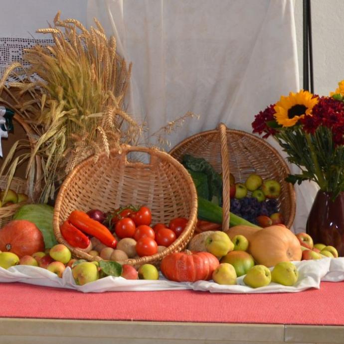 Körbe mit Obst und Gemüse liegen als Erntegaben vor einem Altar.