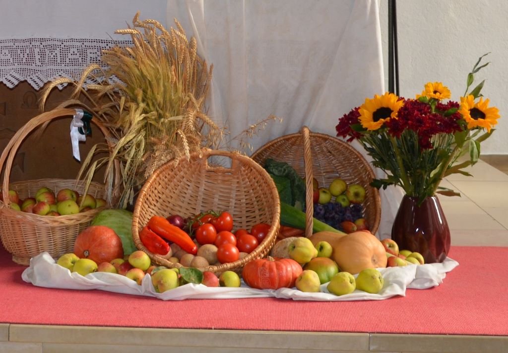 Körbe mit Obst und Gemüse liegen als Erntegaben vor einem Altar.