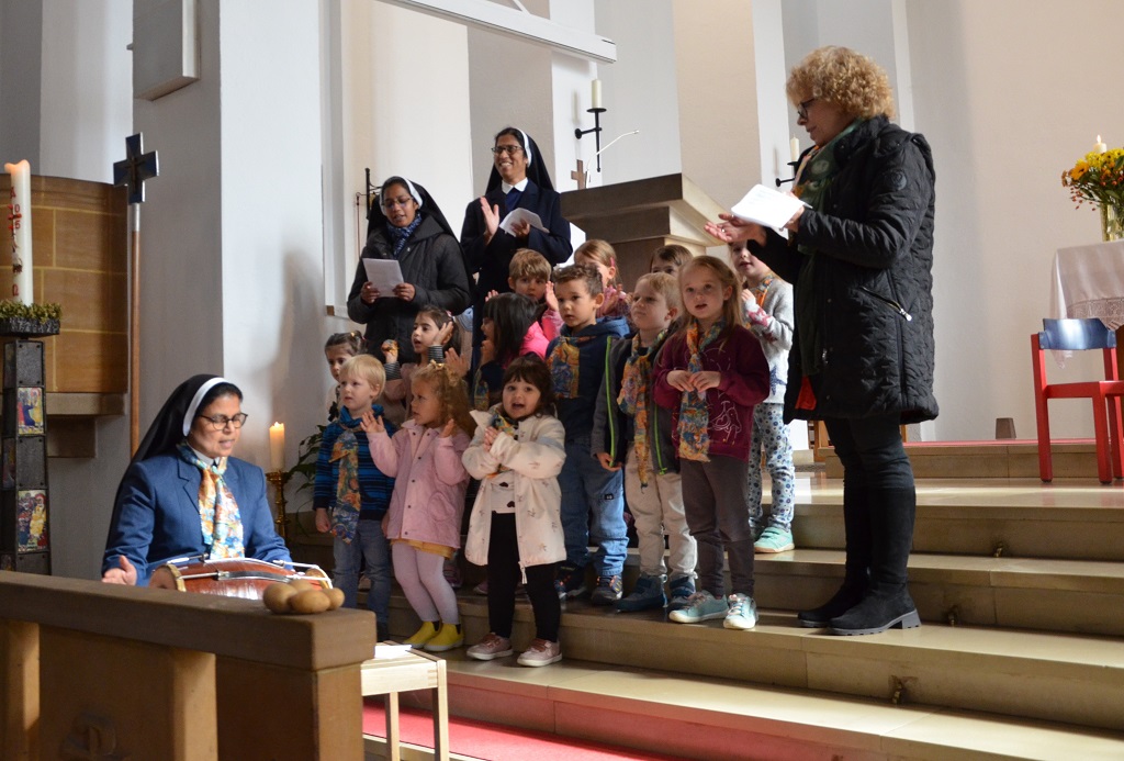 Kindergartenkinder und ihre Erzieherinnen singen in einer Kirche.