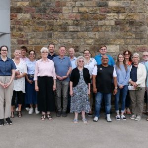 Gruppe von Menschen vor einer hohen Mauer.