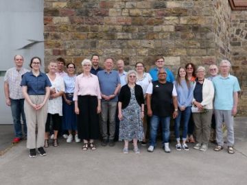 Gruppe von Menschen vor einer hohen Mauer.