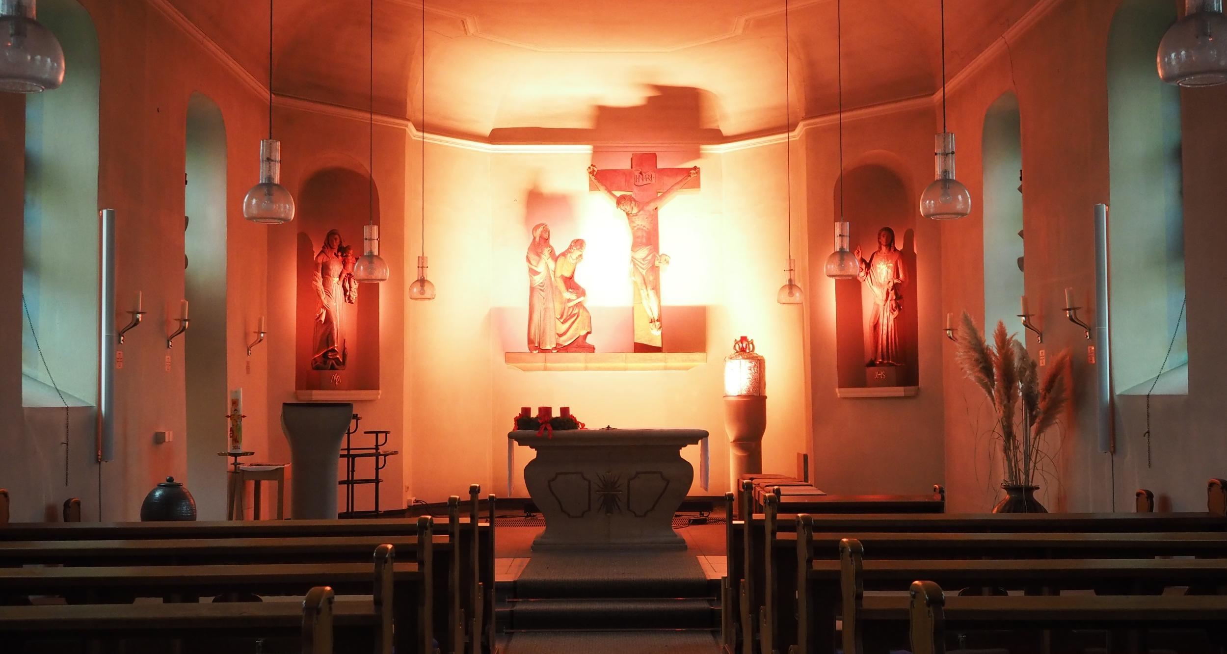 Blick in den gesamten Kirchraum, Altarraum in helles Licht getaucht.