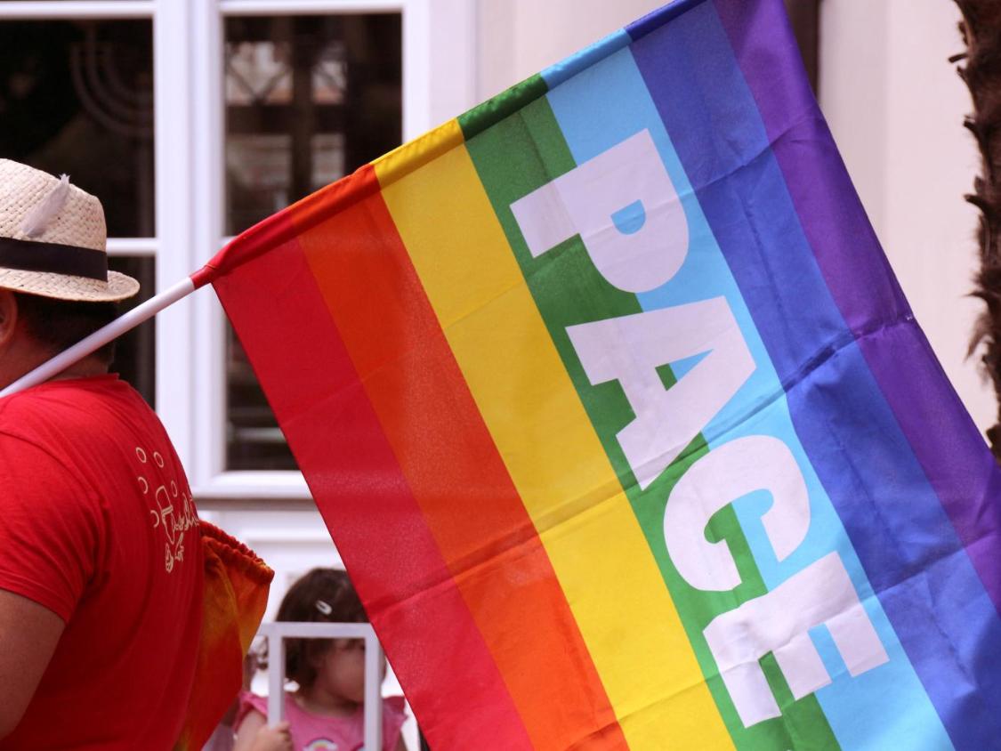 Ein Mann trägt eine Regenbogenfahne mit der Aufschrift Pace