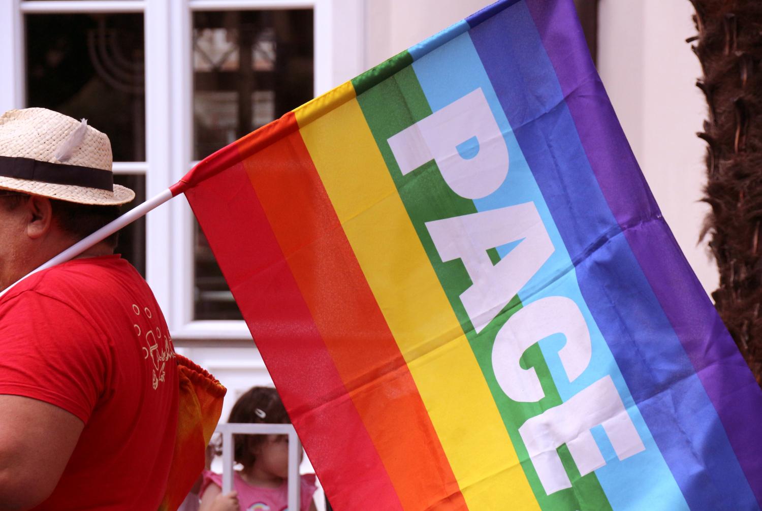 Ein Mann trägt eine Regenbogenfahne mit der Aufschrift Pace