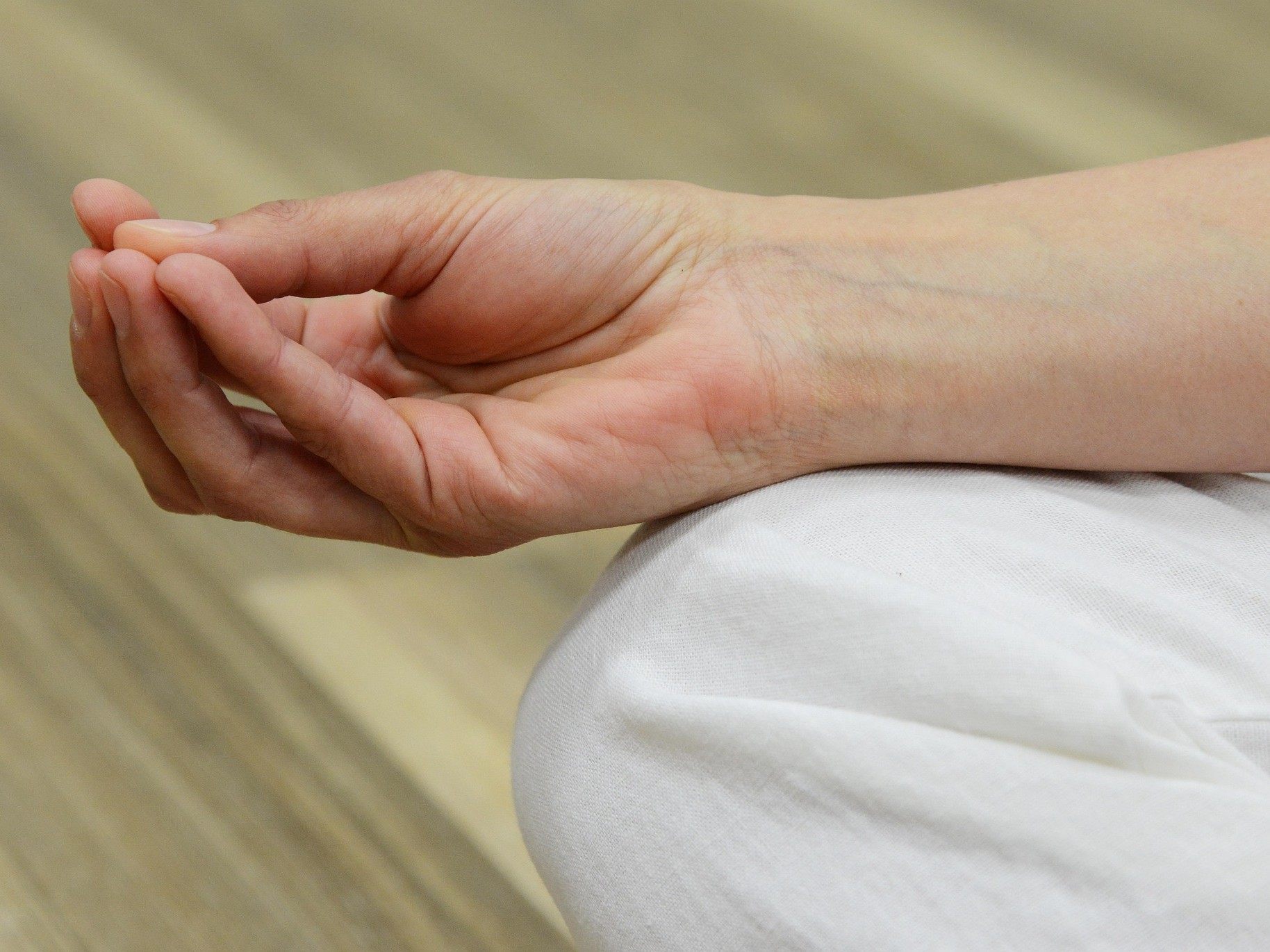 Hand auf Knie mit Yogaposition der Finger