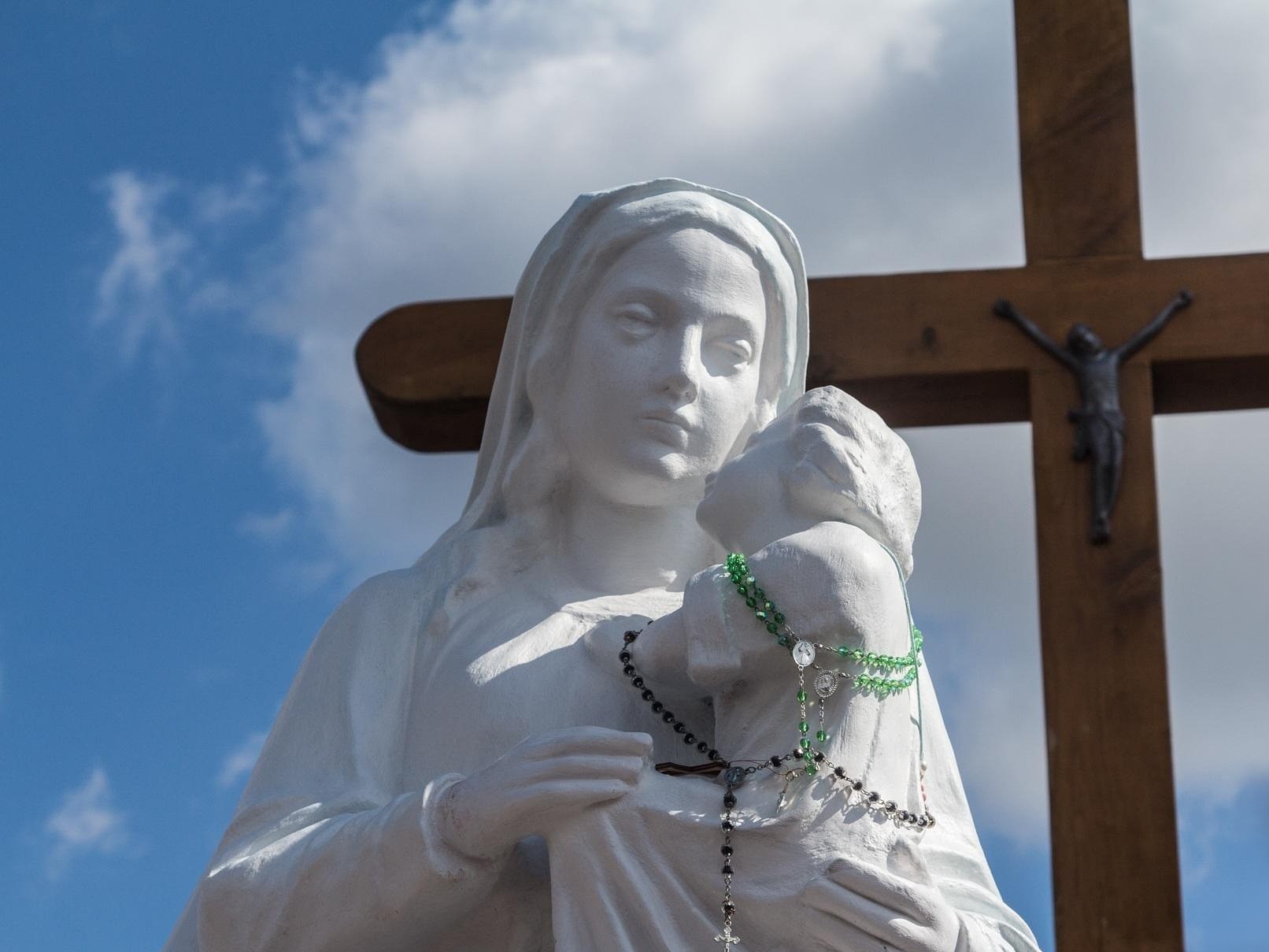 Marienstatue mit Kreuz im Hintergrund