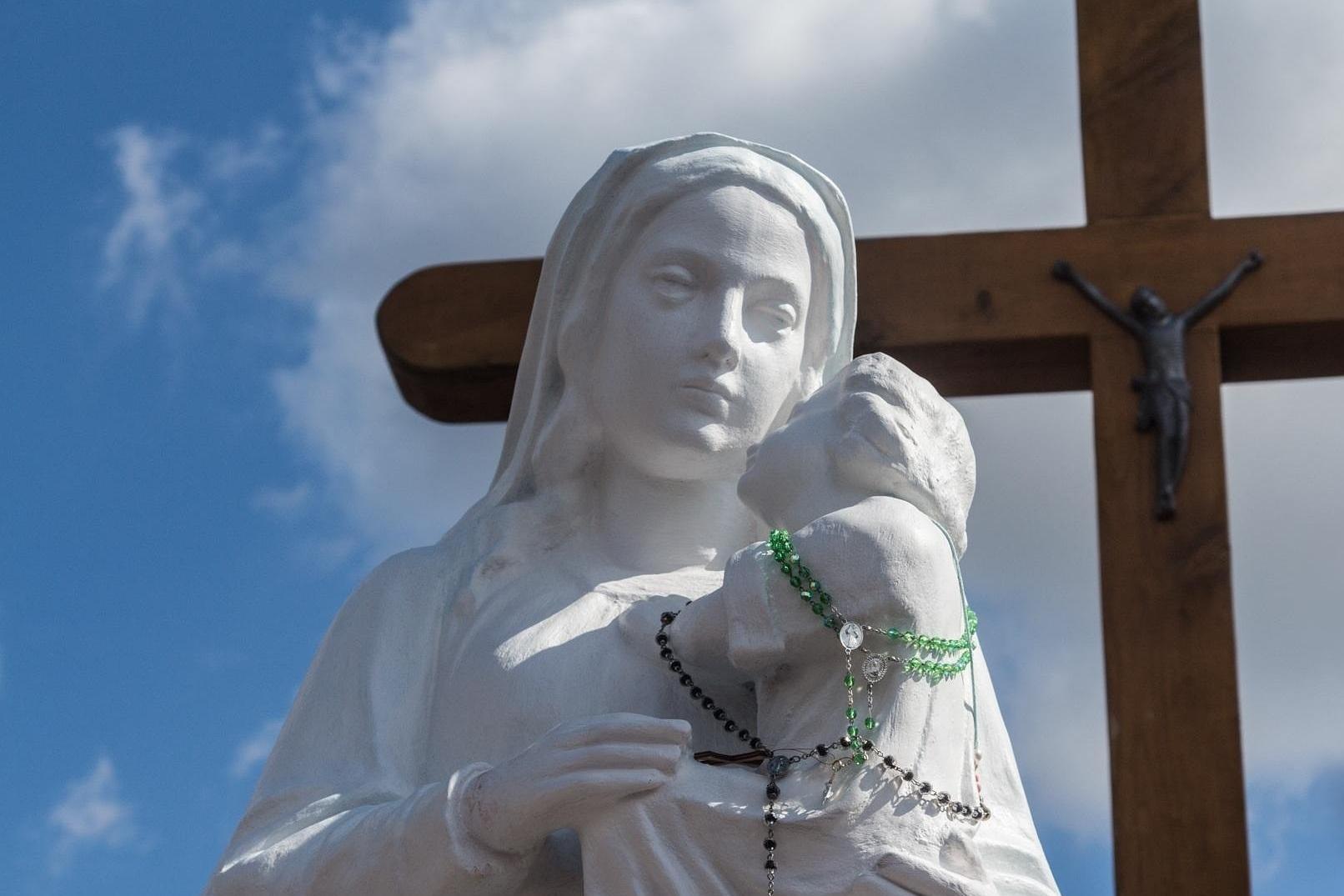 Marienstatue mit Kreuz im Hintergrund
