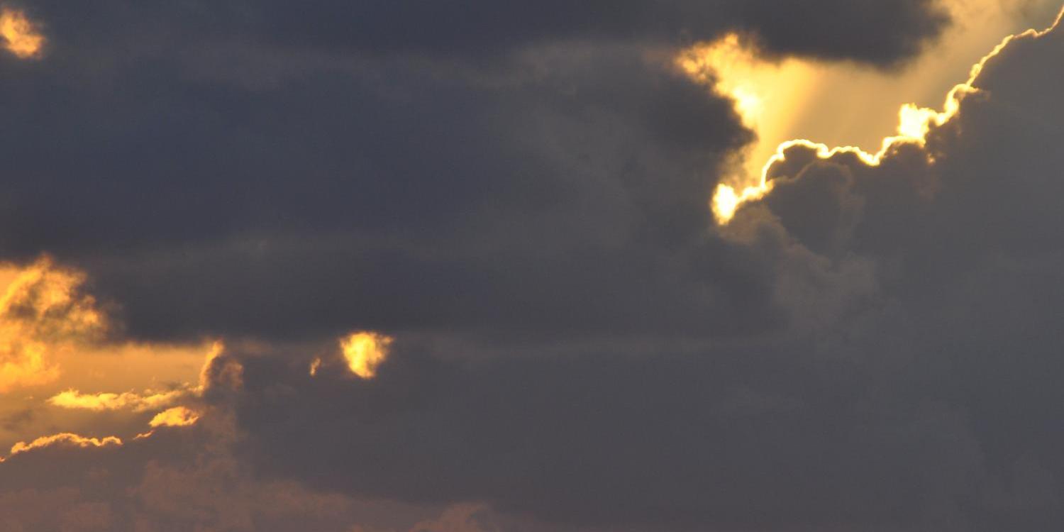 Schwarze Wolken vor goldenem Himmel