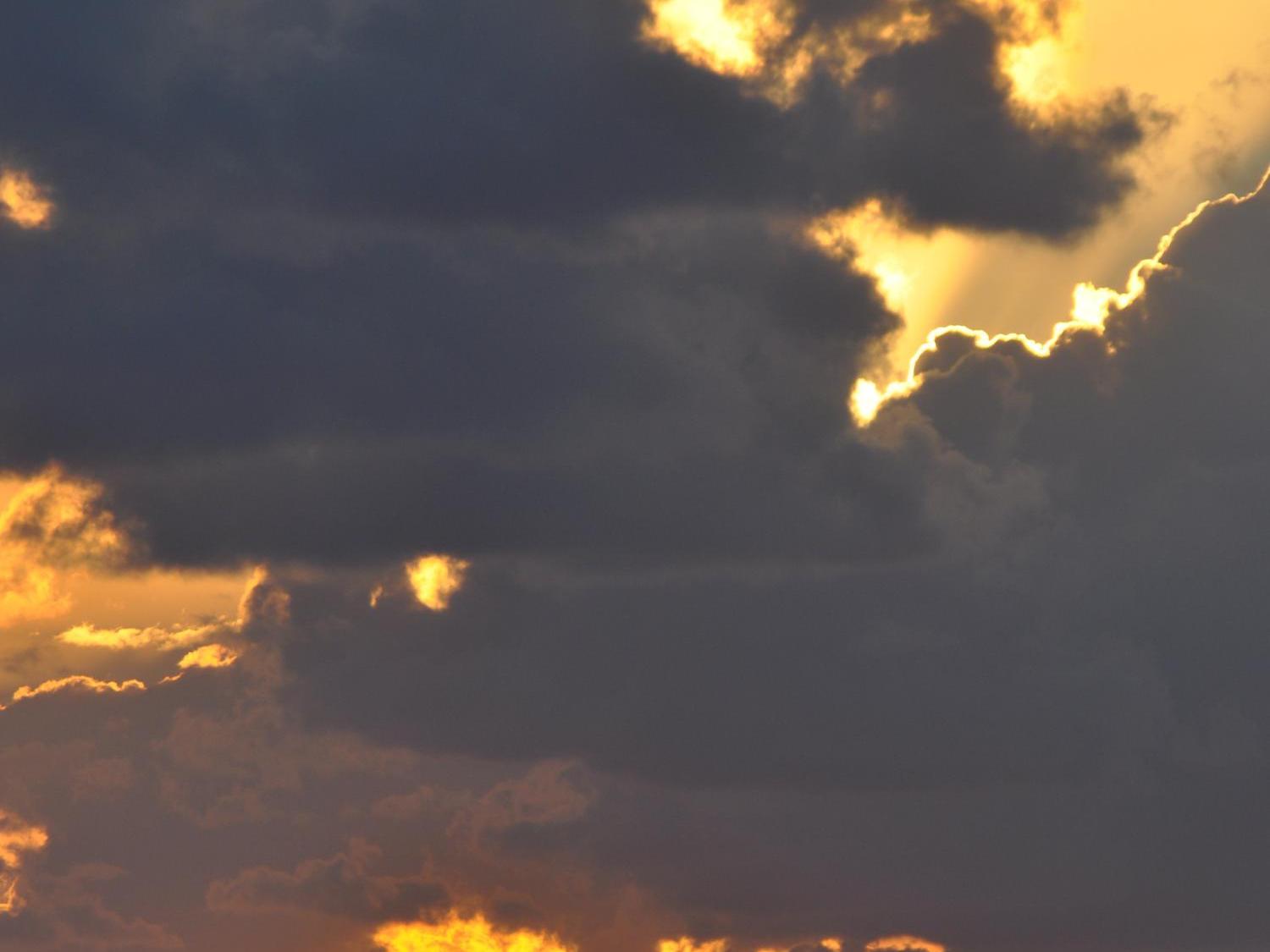 Schwarze Wolken vor goldenem Himmel