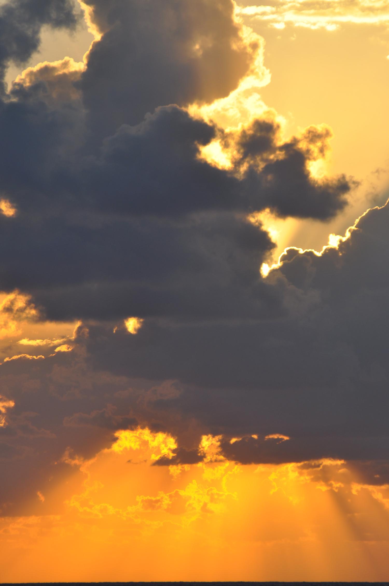 Schwarze Wolken vor goldenem Himmel