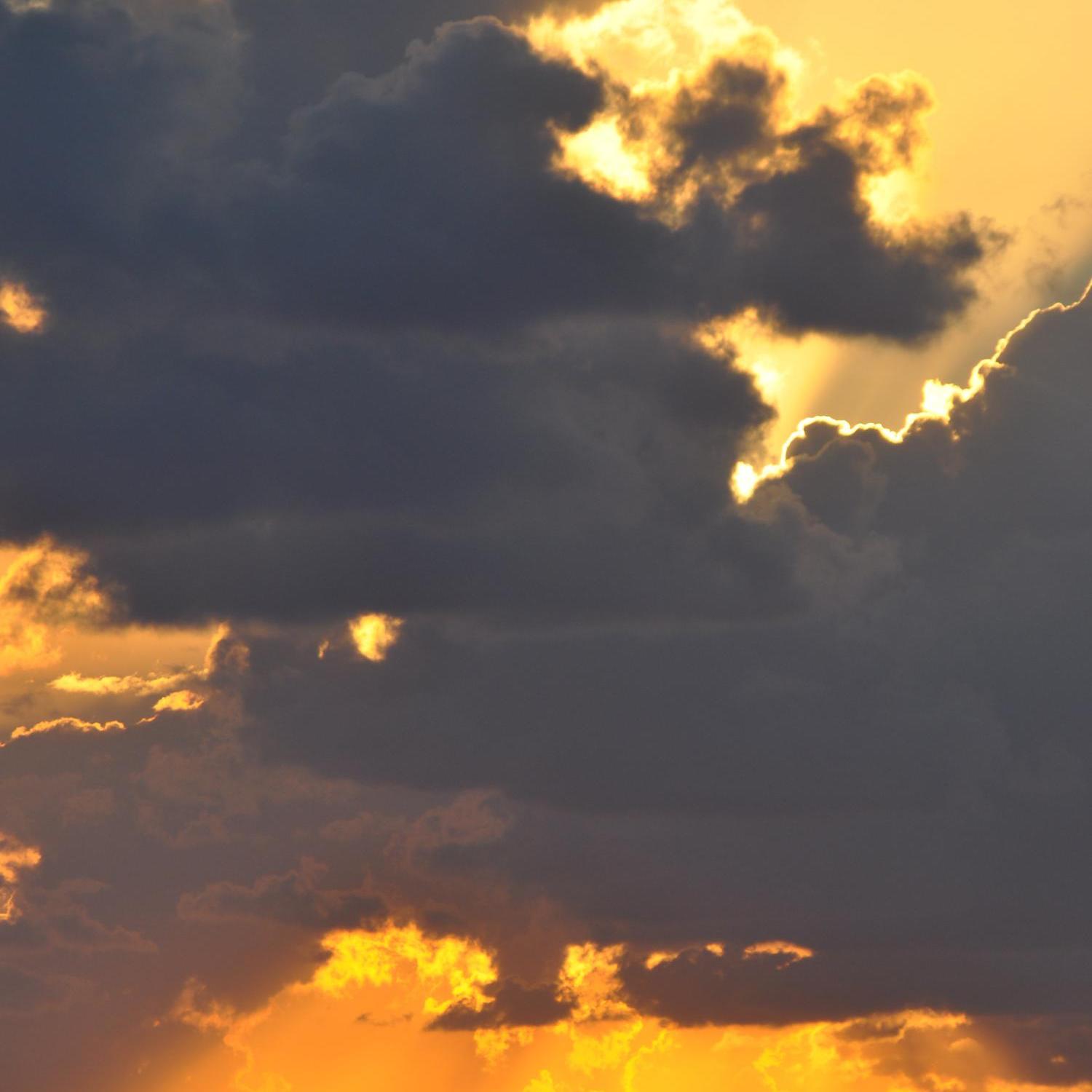 Schwarze Wolken vor goldenem Himmel