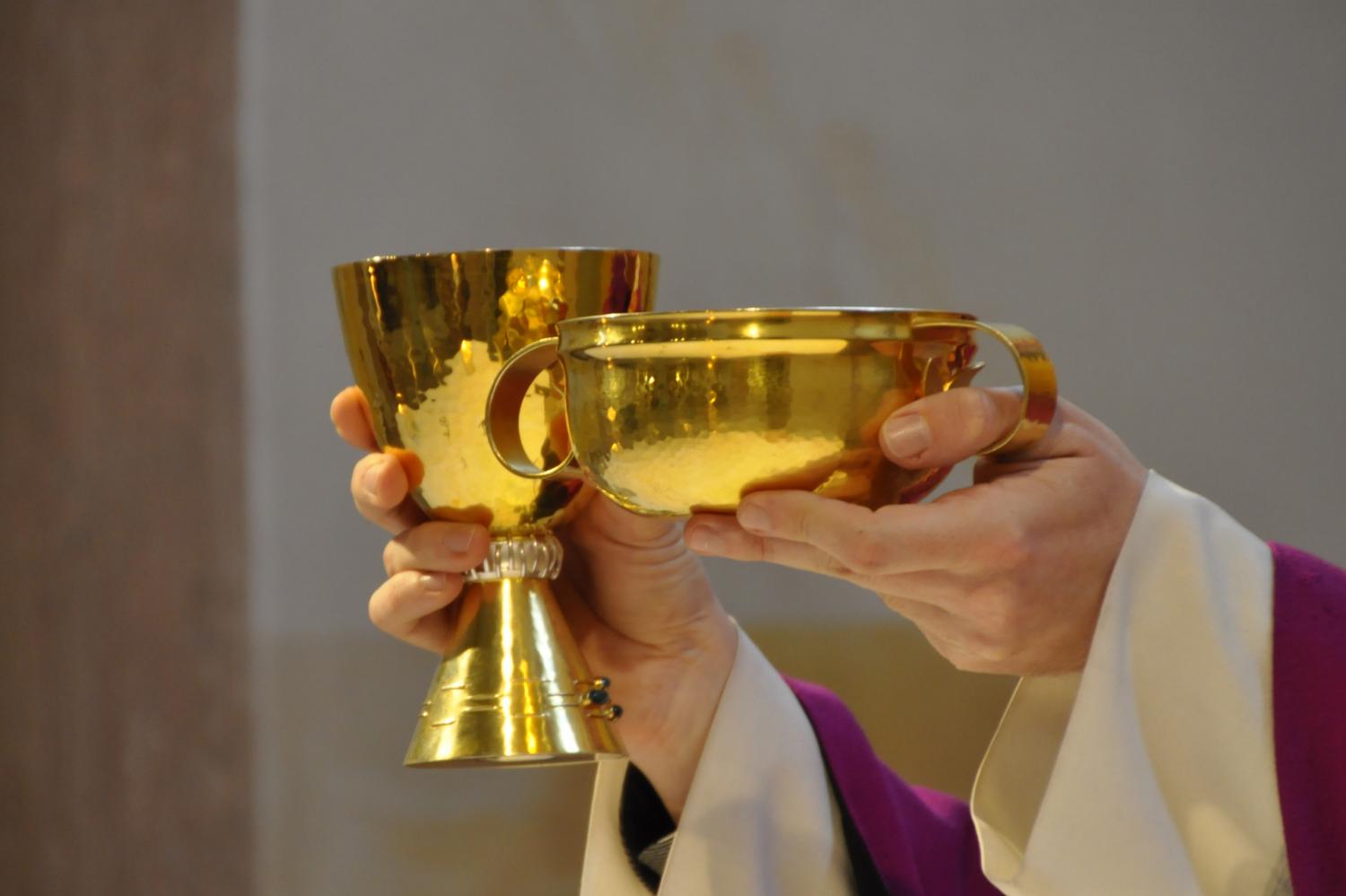 Priesterhände halten Kelch und Hostienschale in die Höhe.