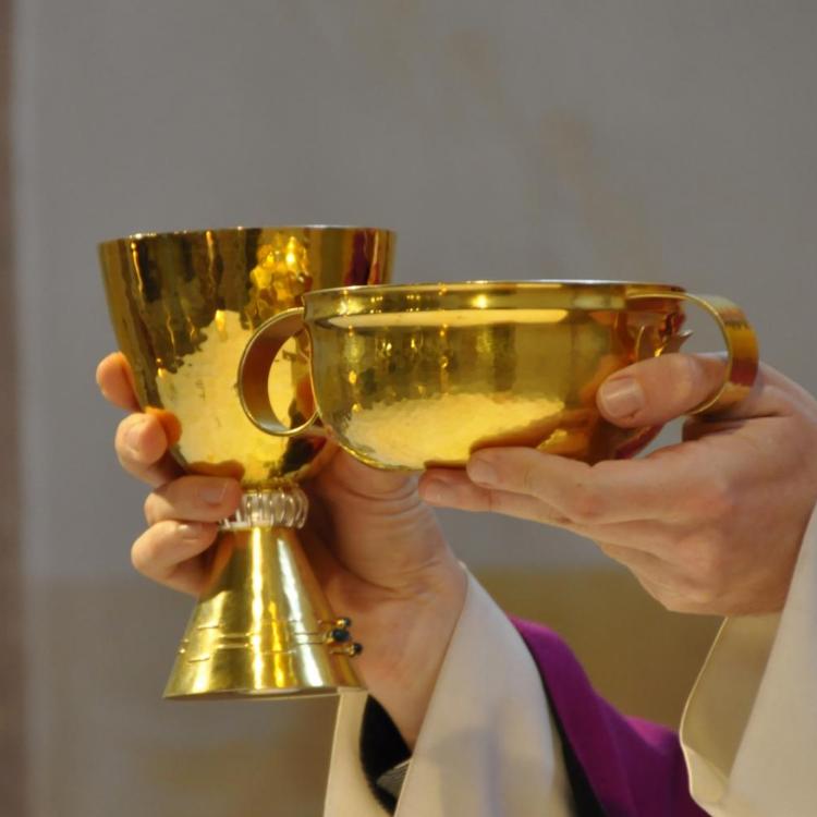 Priesterhände halten Kelch und Hostienschale in die Höhe.