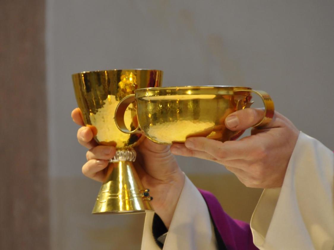 Priesterhände halten Kelch und Hostienschale in die Höhe.