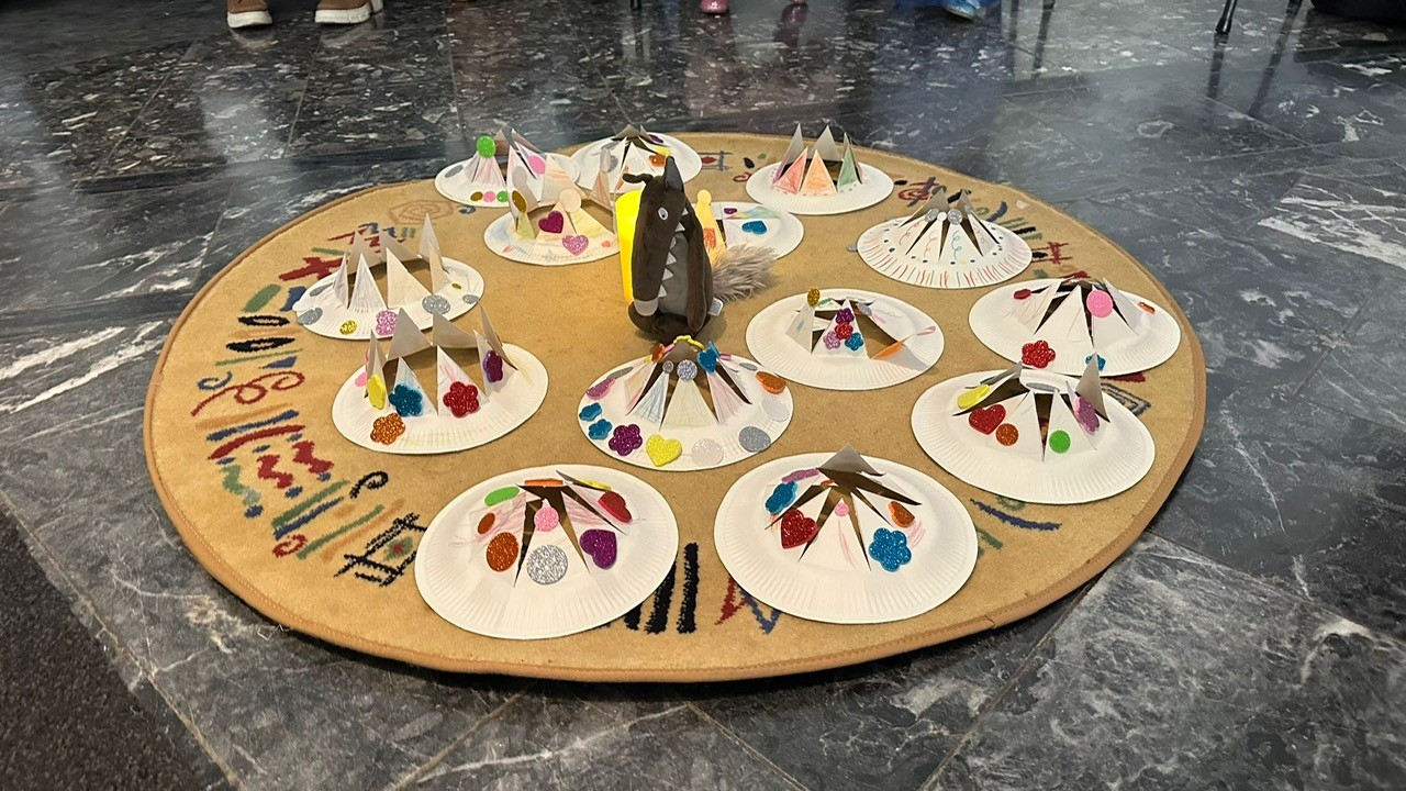 Die bunten Kronen der Kinder rahmen den grauen Wolf ein