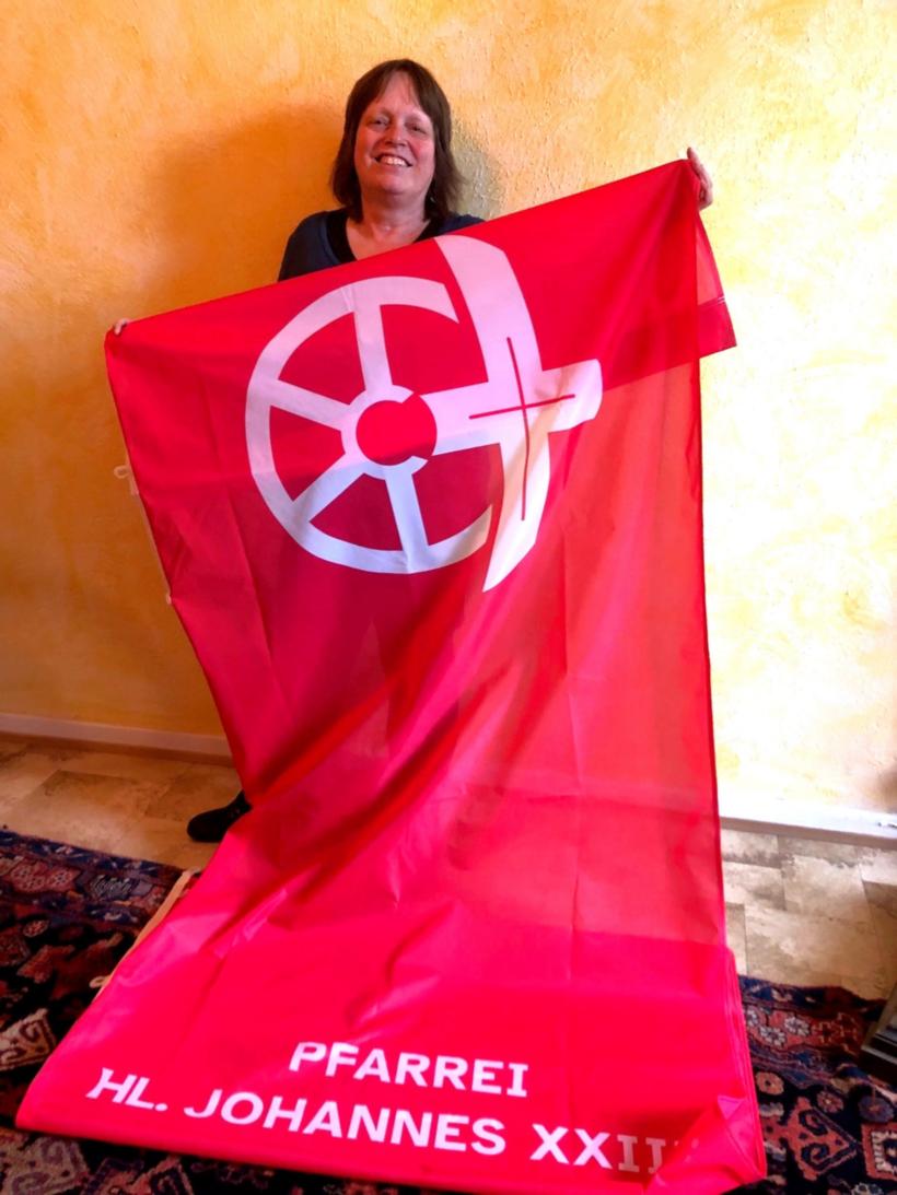 Küsterin Monika Brößner zeigt die Fahne mit dem neuen Logo.