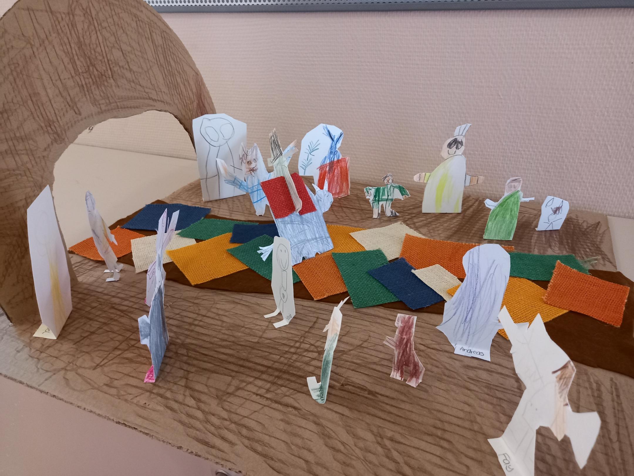 einzelne Pappfiguren stehen auf einem gestalteten Weg, der zu einem Tor führt