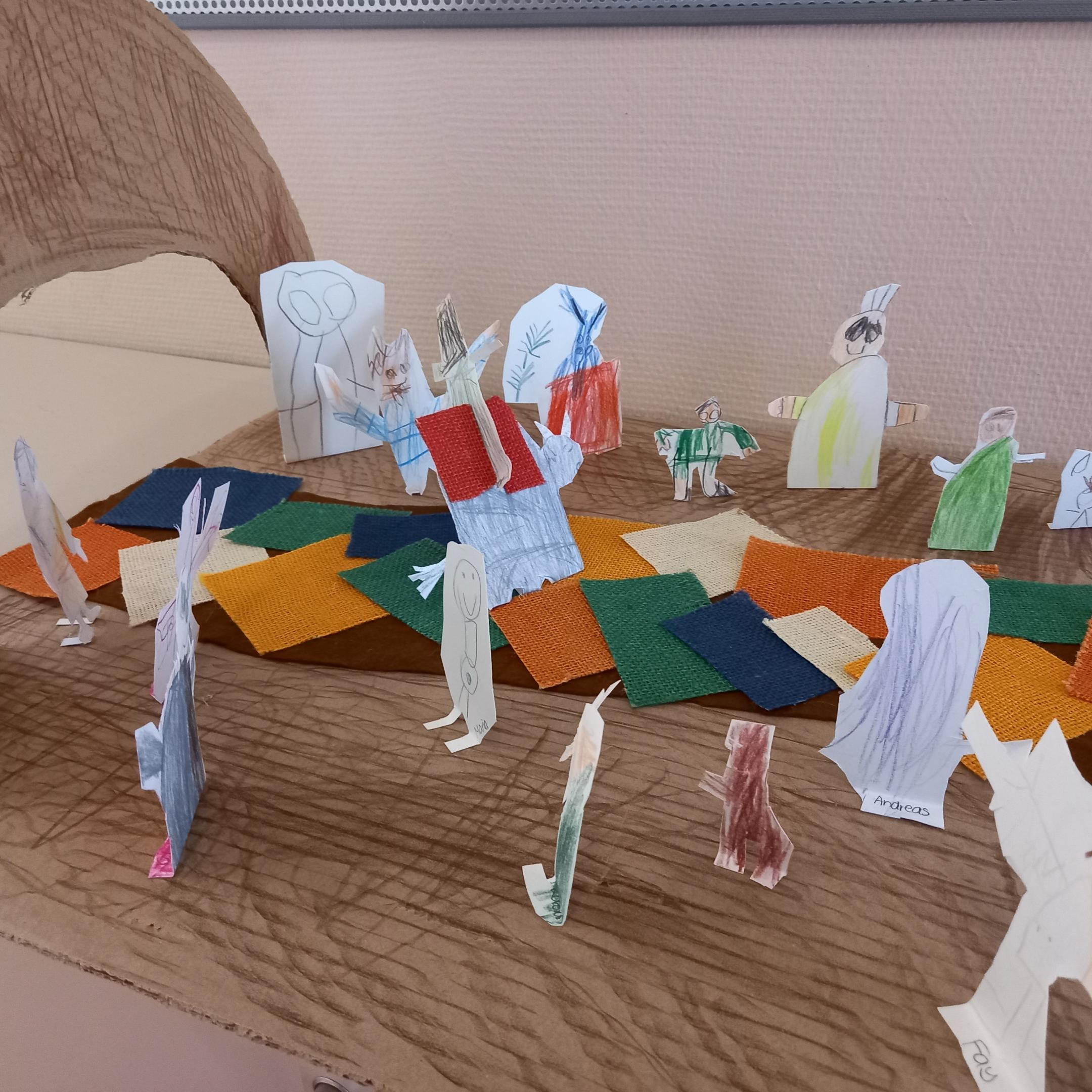 einzelne Pappfiguren stehen auf einem gestalteten Weg, der zu einem Tor führt