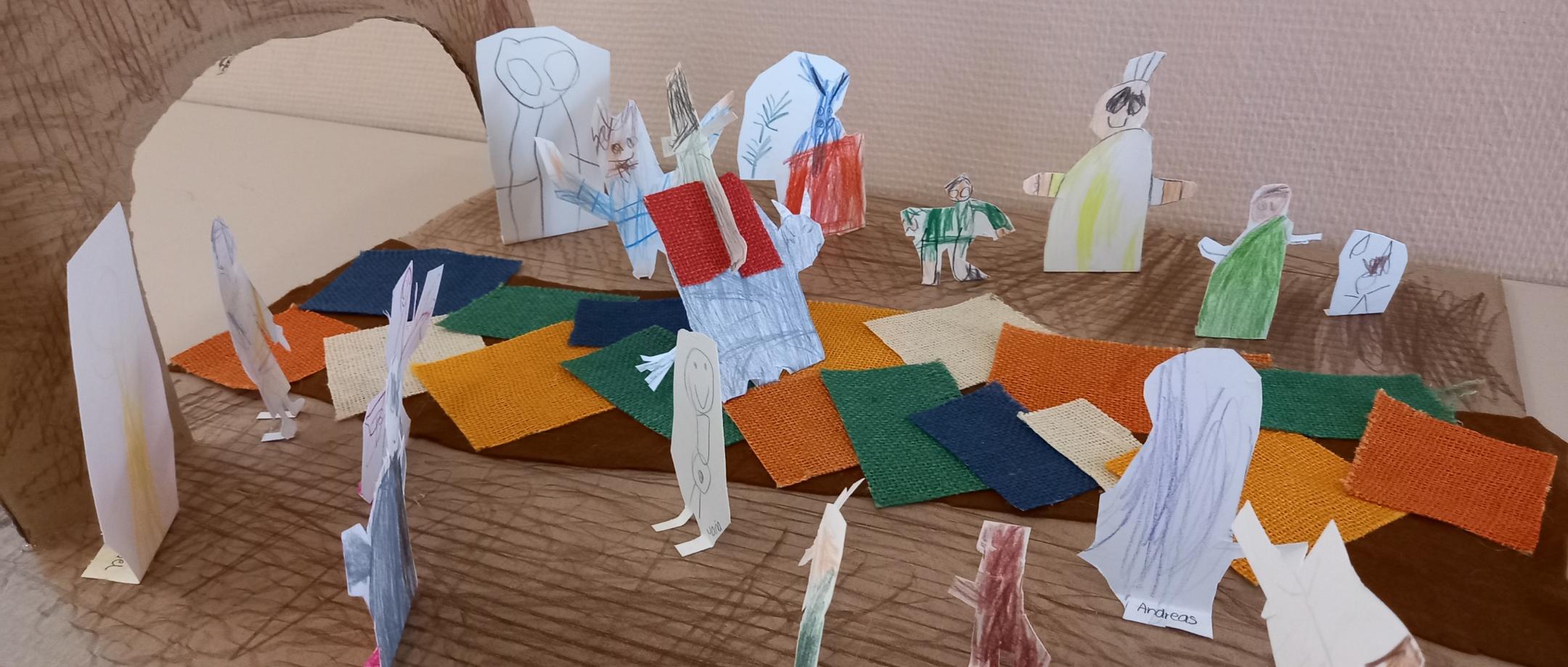 einzelne Pappfiguren stehen auf einem gestalteten Weg, der zu einem Tor führt