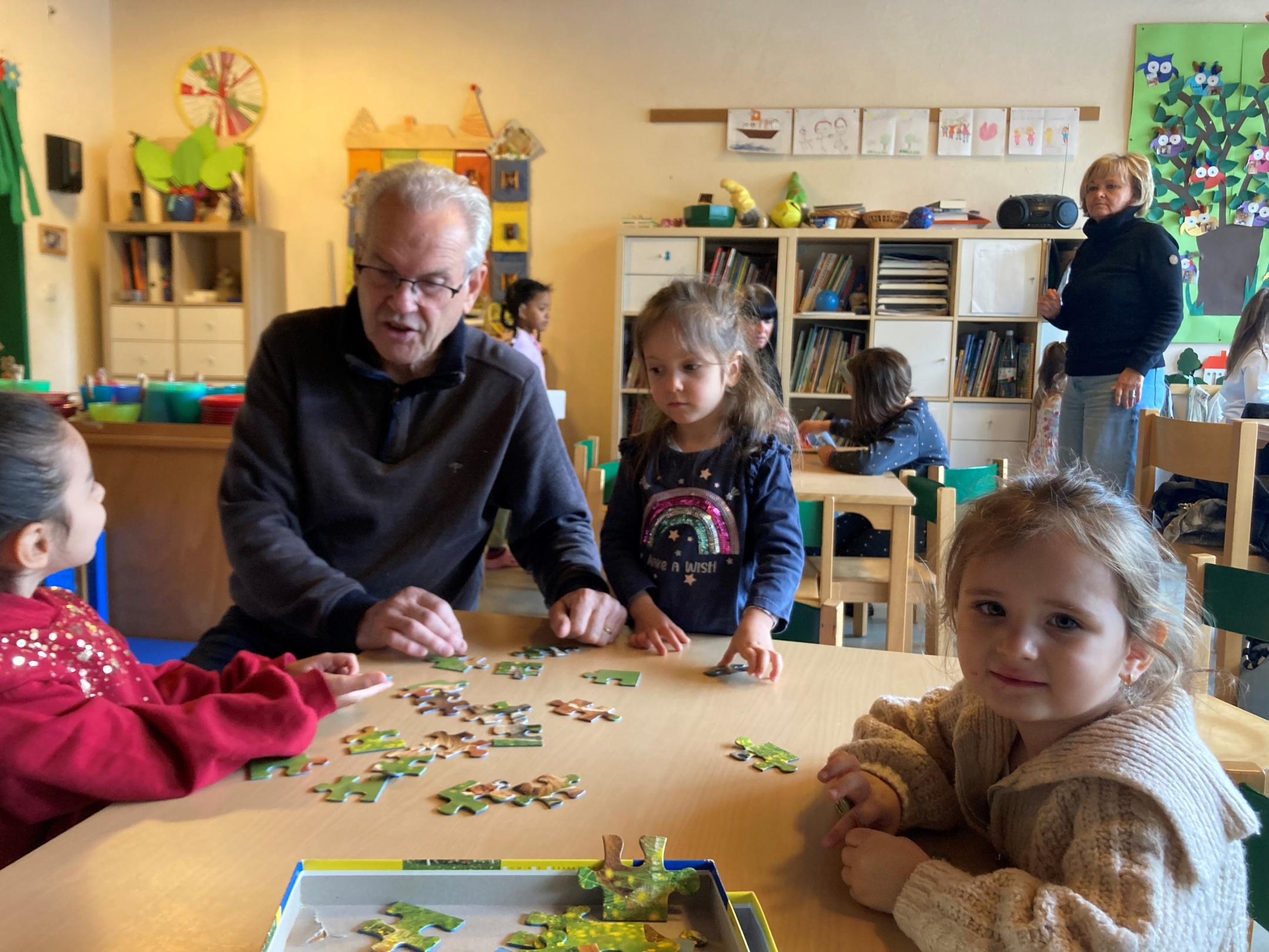 Sprachpate Wolfgang Knapp puzzlet mit Kindern in der WIchtelgruppe
