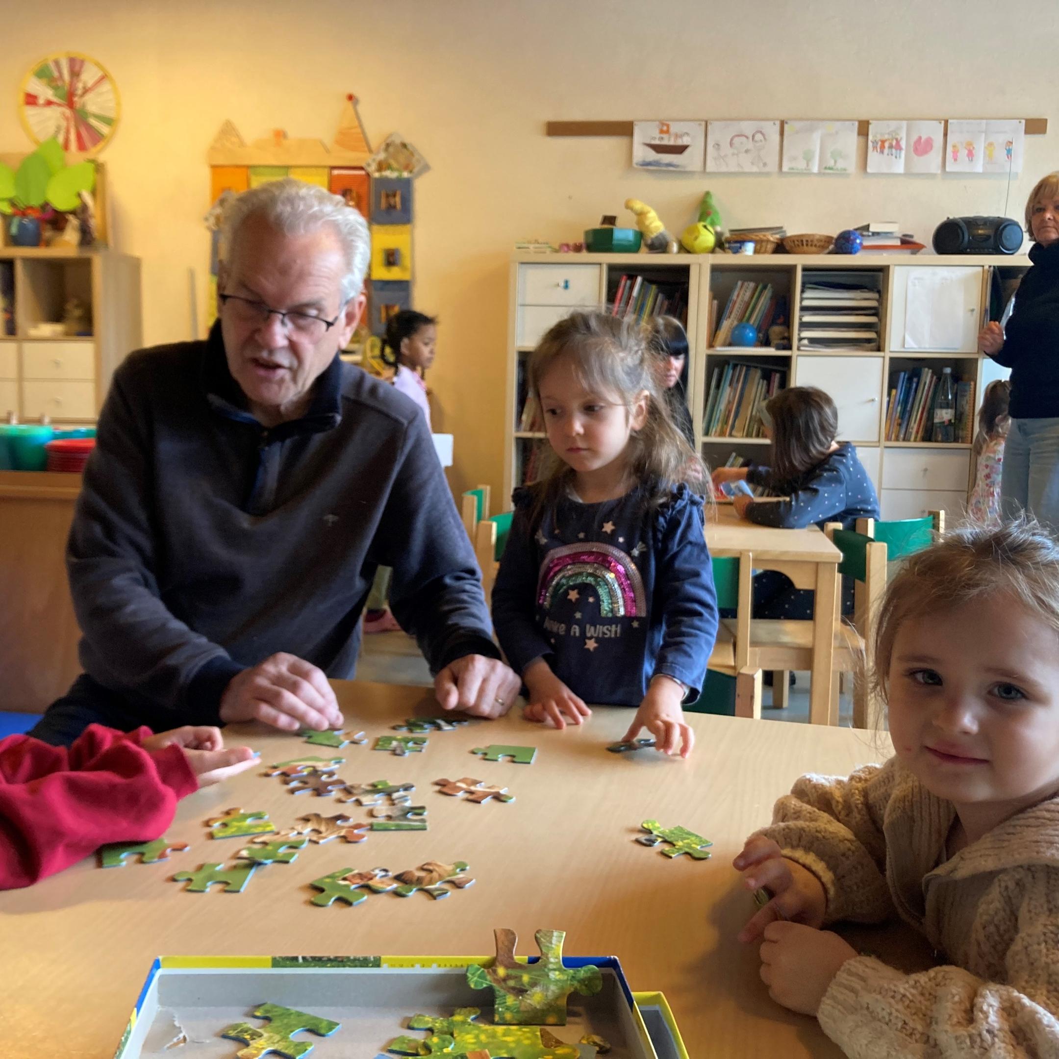 Sprachpate Wolfgang Knapp puzzelt mit Kindern in der Wichtelgruppe