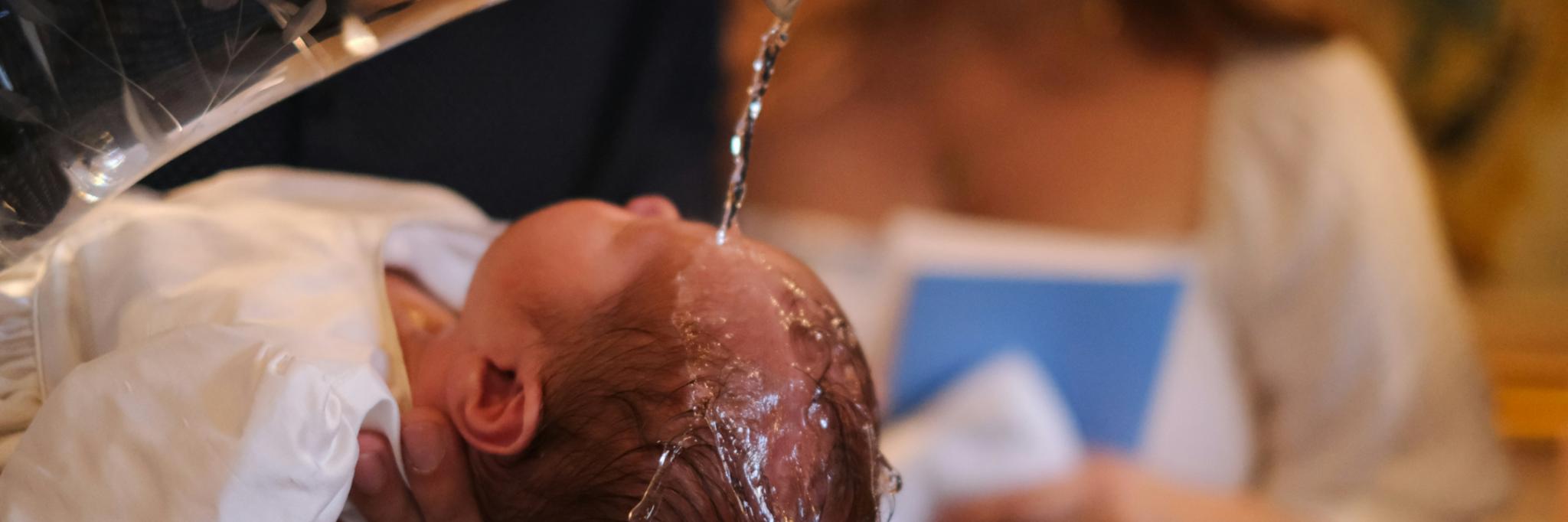 ein Baby wird mit Wasser übergossen