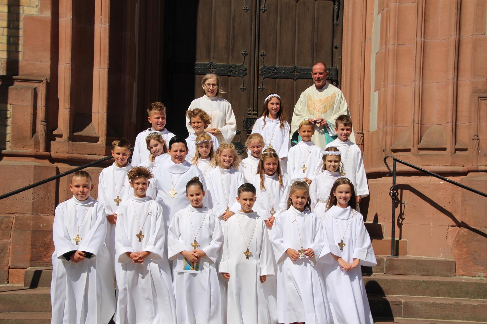 Die Kommunionkinder stehen auf den Stufen vor dem Hauptportal der Kirche.