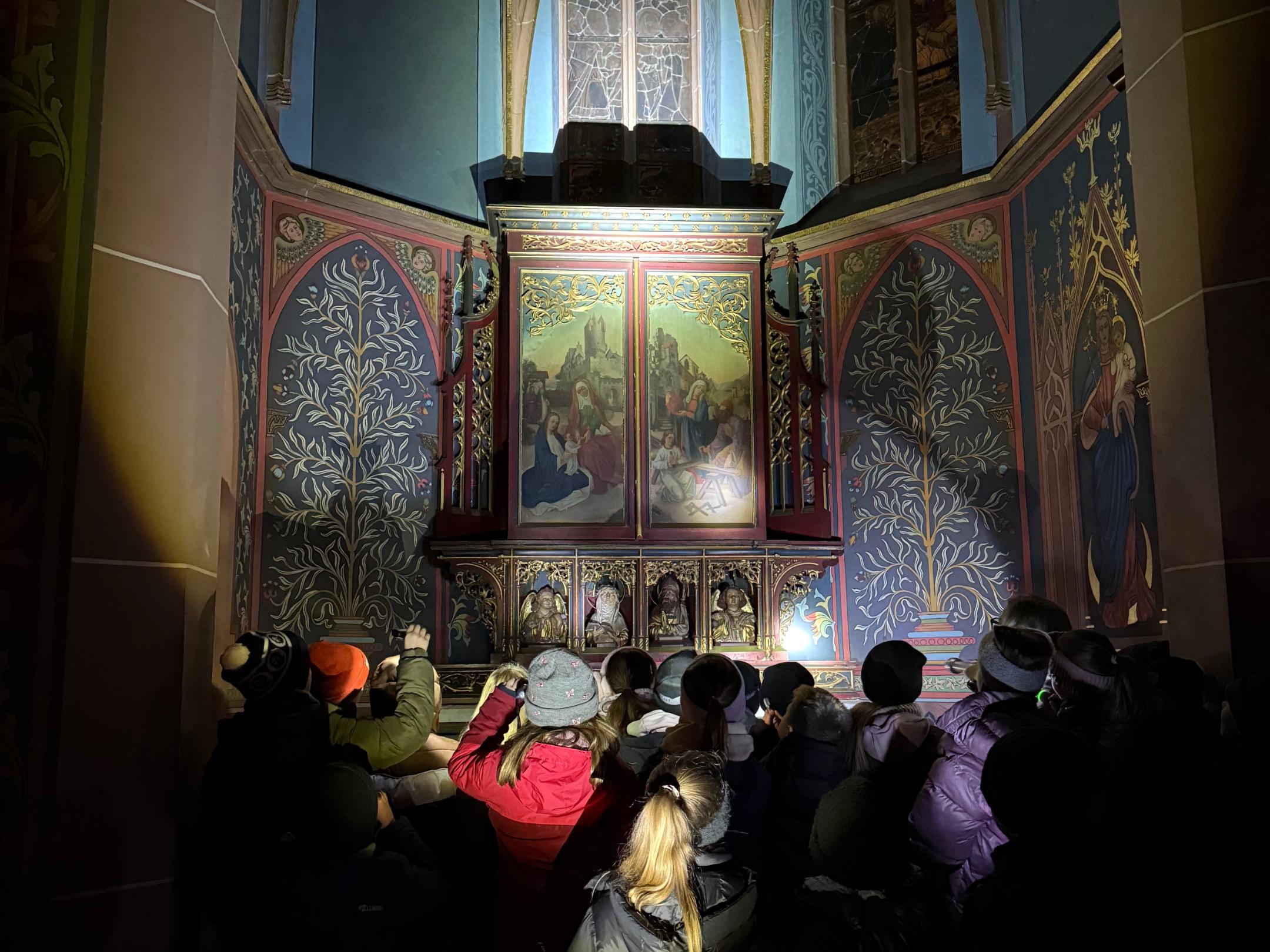 Mit Taschenlampen entdecken die Kommunionkinder die Apostelkirche.